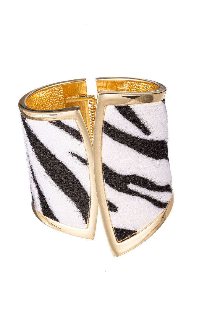 Wide open cuff bracelet with a black and white zebra print design and gold-tone metal edges.