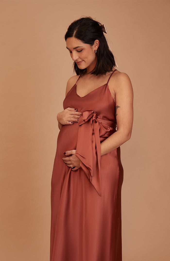 Woman wearing a rust-colored dress against a beige background