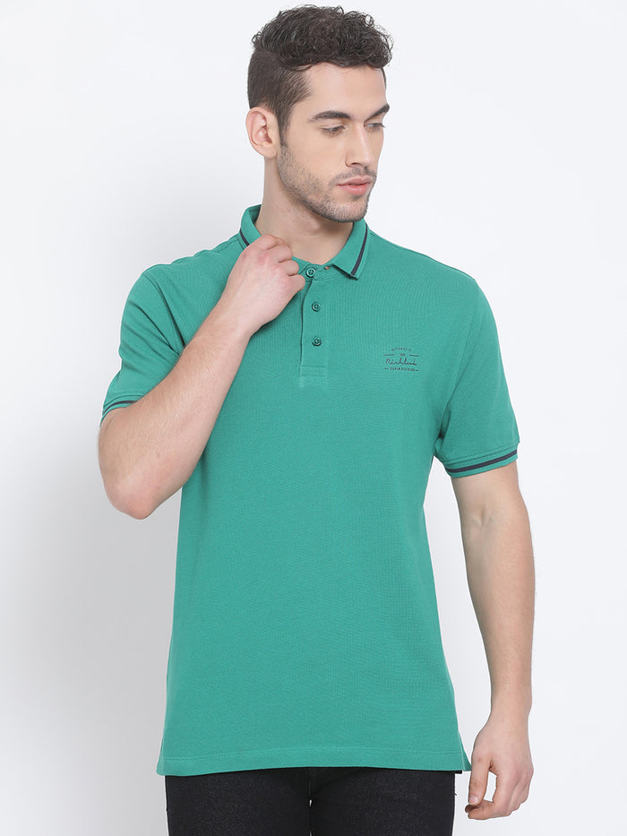 A man wearing a green solid polo neck t-shirt.