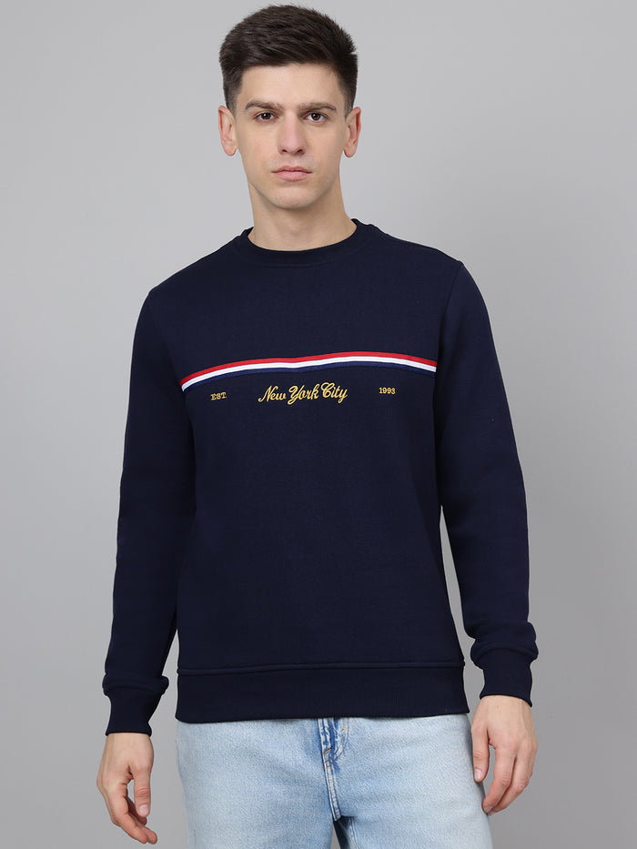 Man wearing a navy blue sweatshirt with 'New York City' text and red, white, and blue stripe on a gray background