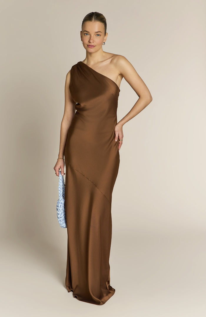 Woman wearing a brown one-shoulder dress against a beige background