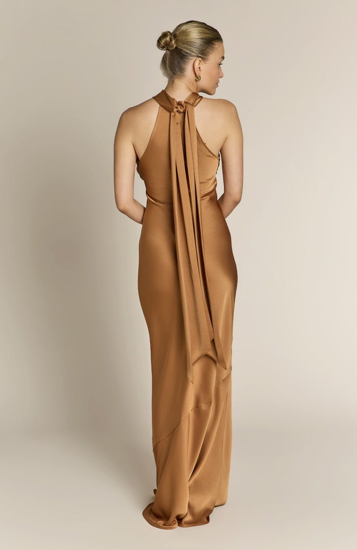 Woman wearing a long brown dress against a beige background