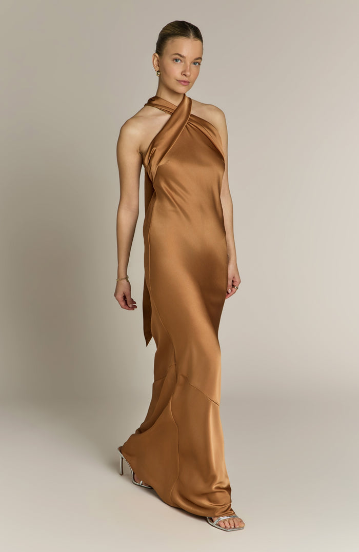 Woman wearing a long brown dress against a neutral background