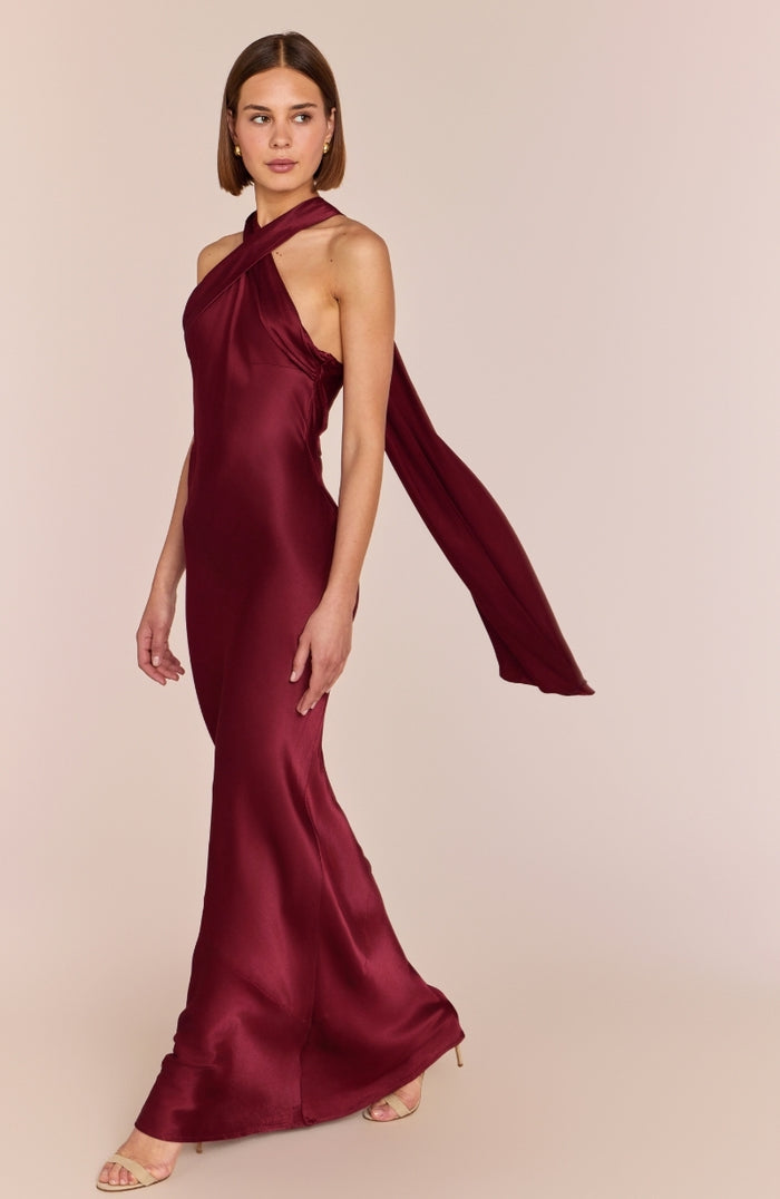 Woman wearing a burgundy halter neck gown on a beige background